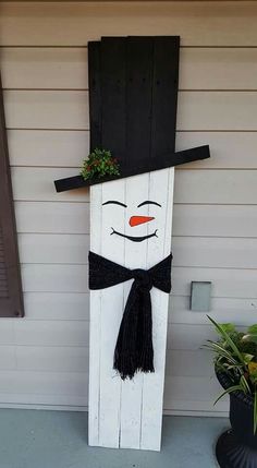 a wooden snowman with a black hat and bow tie on it's head