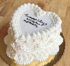 a heart shaped cake with writing on it sitting on top of a wooden table next to a knife