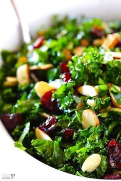 a white bowl filled with greens and nuts