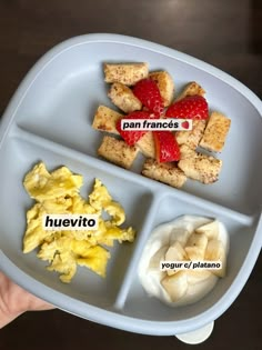 a person holding a plate with food on it that includes tofu, cheese and strawberries