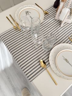 the table is set with gold and white plates, silverware, and napkins