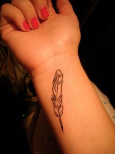 a woman's arm with a small feather tattoo on it