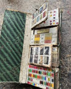 an open book with many different colored papers on it's cover, sitting against a stone wall