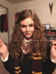 a young woman wearing a harry potter costume holding up a string with her hands in front of her face