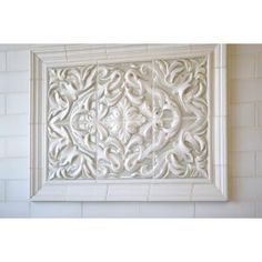 a white tile wall with an intricate design on it's face and bottom part