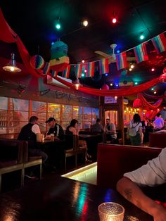 a man sitting at a table in front of a bar filled with people eating and drinking