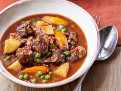 a white bowl filled with beef and potatoes