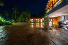 a car is parked in front of a house at night with its lights on and water running down the driveway