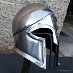 a close up of a metal helmet on a wooden stand in front of a brick wall