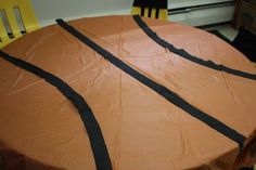 a basketball shaped cake sitting on top of a wooden table with black ribbon around it