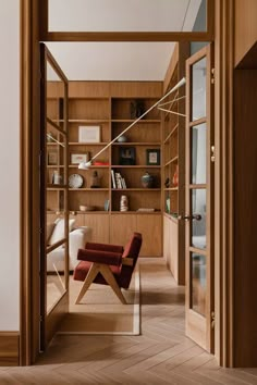 a chair sitting in front of a wooden book shelf next to a doorway with glass doors