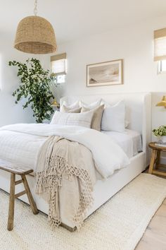 a bed with white sheets and pillows in a bedroom next to two pictures on the wall