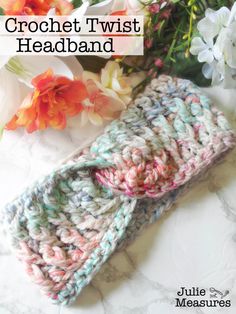 the crochet twist headband is laying next to flowers