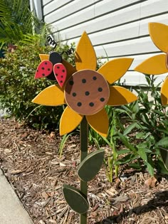 two wooden sunflowers with ladybugs on them in front of a house