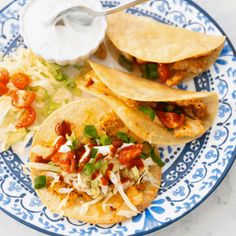 three tacos are on a blue and white plate