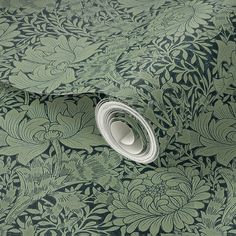 a green floral wallpaper with black and white flowers on the bottom half of it