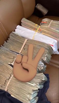 a stack of papers with a peace sign drawn on it's middle finger, sitting on top of a leather chair