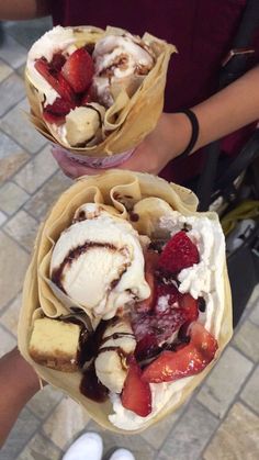 two people holding some very tasty looking pastries with ice cream and strawberries