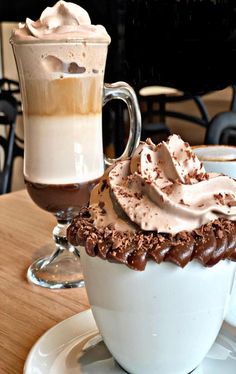 there is a cup of coffee with whipped cream on top and a drink in the background