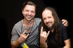 two men with long hair and beards posing for the camera, one holding his finger up