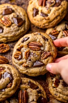 chocolate chip cookies with pecans in the middle being held by someone's hand