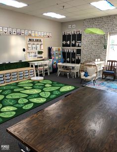 a classroom with tables, chairs and rugs on the floor in front of windows