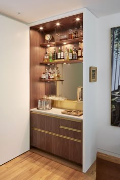 a kitchen with wooden flooring and shelves filled with bottles, glasses, and other items