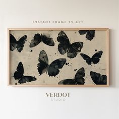 a black and white butterfly painting hanging on the wall next to a wooden frame that says instant frame tv art