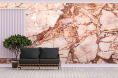 a black couch sitting in front of a wall covered in pink and gold marble tiles