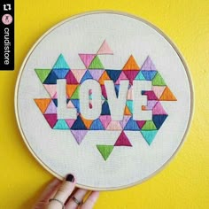 someone is holding up a colorful cross stitched love sign