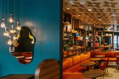 the interior of a restaurant with orange and blue booths, round tables, and circular mirrors