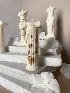 three white vases sitting on top of a marble slab with flowers in the background