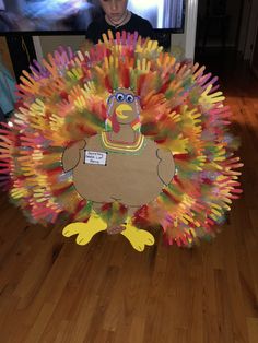 a child standing in front of a turkey made out of crayons