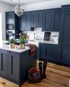 a kitchen with dark blue cabinets and white counter tops, an island in the middle