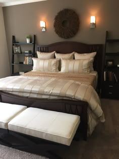 a bedroom with a bed, two lamps and a book shelf on the wall above it