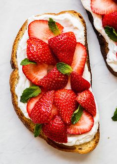 two pieces of bread with whipped cream and strawberries on top, next to each other