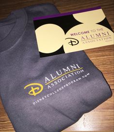 a t - shirt and business card sitting on a wooden table next to each other