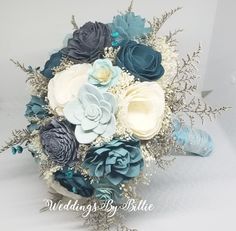 a bridal bouquet with blue, white and grey flowers on the bottom is shown