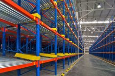 the inside of a large warehouse filled with metal shelving and yellow bars on each side