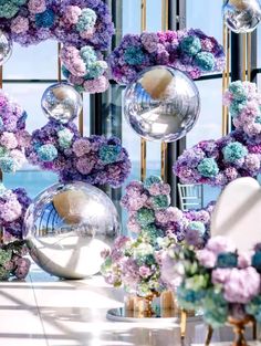 purple and blue flowers are hanging in front of a window with large glass balls on it