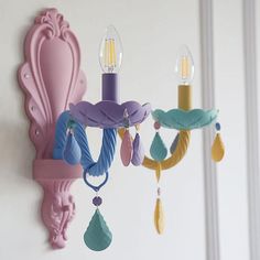 a colorful chandelier hanging from the side of a wall next to a mirror