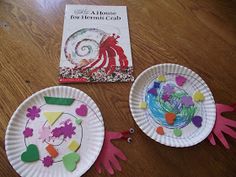 two paper plates with handprinted designs on them next to a book and craft kit