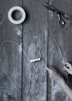 someone is working with wire and scissors on a wooden table next to a pair of scissors