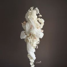 a wedding cake with white flowers on top and a candle in the middle, against a dark background