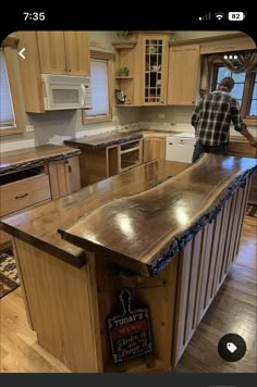 a man standing at the top of a kitchen island in front of an oven and microwave