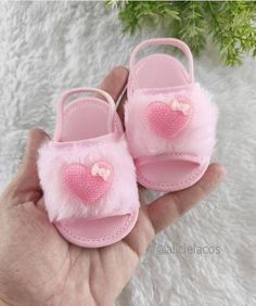 a hand holding a pair of pink baby shoes