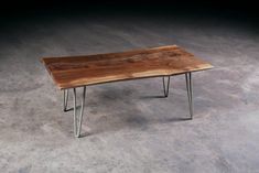 a wooden table sitting on top of a cement floor next to a metal leg rest