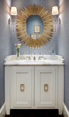 a bathroom vanity with two sinks and a large sun mirror on the wall above it