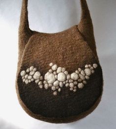 a brown purse with white flowers on the front and bottom, hanging from a hook