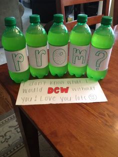 six green water bottles sitting on top of a wooden table next to a sign that says prom